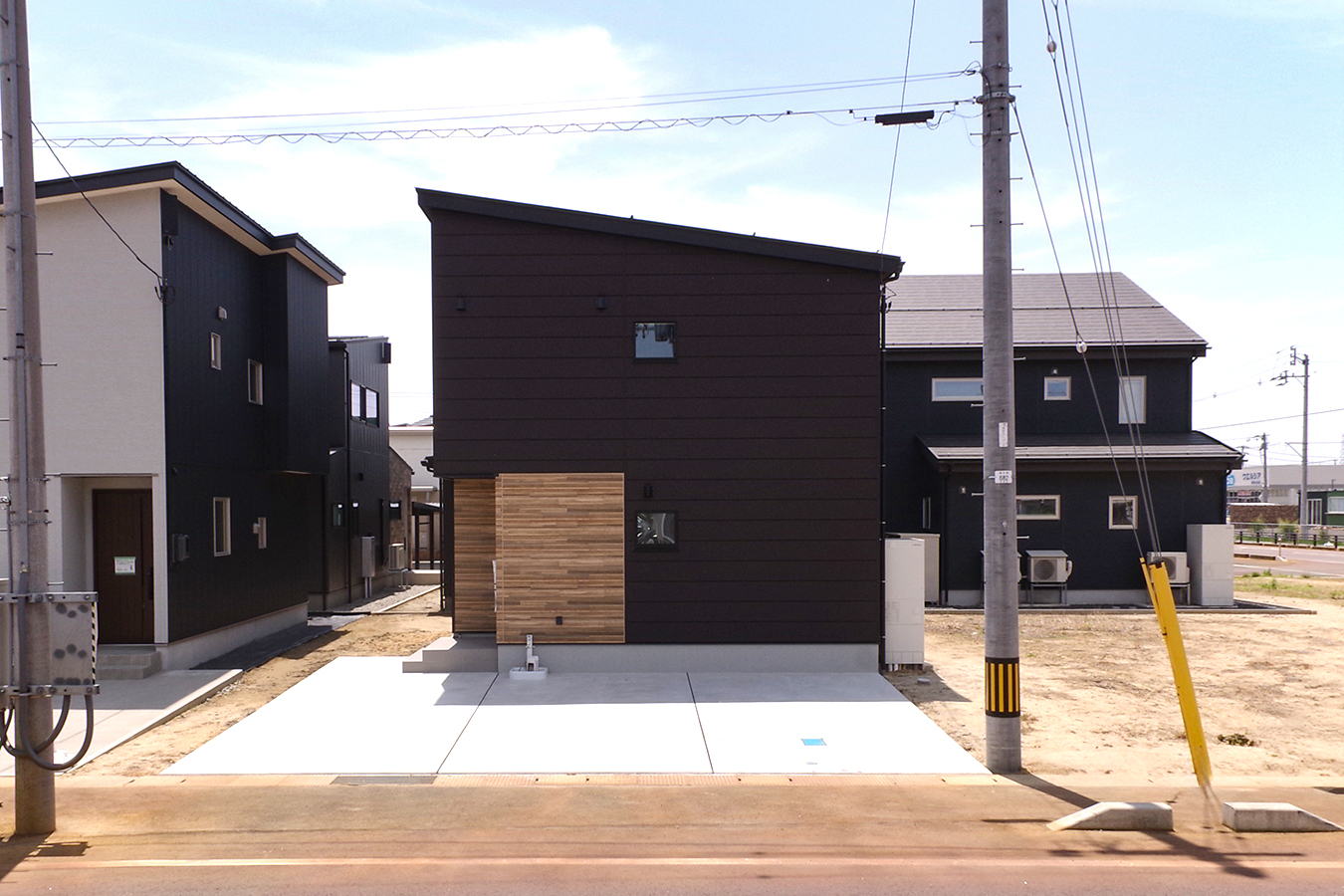 黒色の外壁をメインに木調の外壁でアクセントを効かせた住宅建物外観